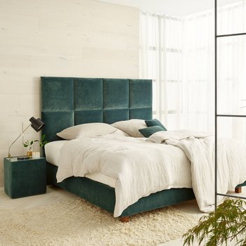 Modernes JOKA Piazza Boxspringbett mit grünem Samt-Kopfteil und hellem Bettzeug in hellgrünem Schlafzimmer