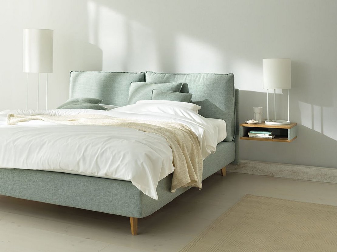 JOKA Arte Boxspringbett in Hellgrün mit weißer Bettwäsche und Holzfüßen im hellen Schlafzimmer