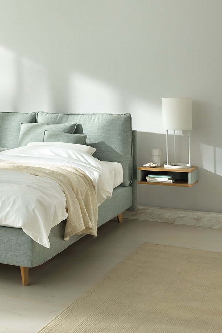 JOKA Arte Boxspringbett in Hellgrün mit weißer Bettwäsche und Holzfüßen im hellen Schlafzimmer