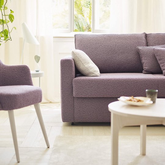 OKA Onda Doppelliege in Lila im Wohnzimmer mit passendem Sessel und Pflanzen.