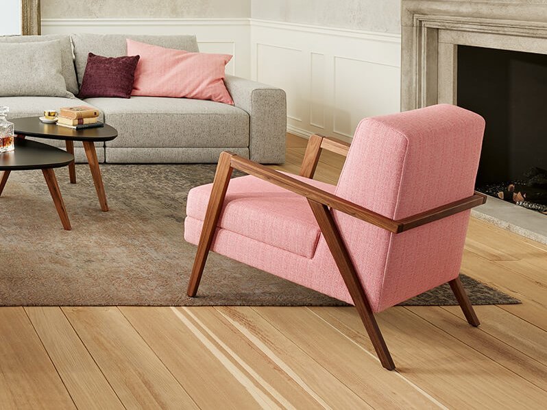 Joka Laguna großzügige graue Wohnlandschaft mit rosa Sessel, dunkelviolettem Hocker und Kamin