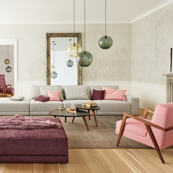 Joka Laguna großzügige graue Wohnlandschaft mit rosa Sessel, dunkelviolettem Hocker und Kamin