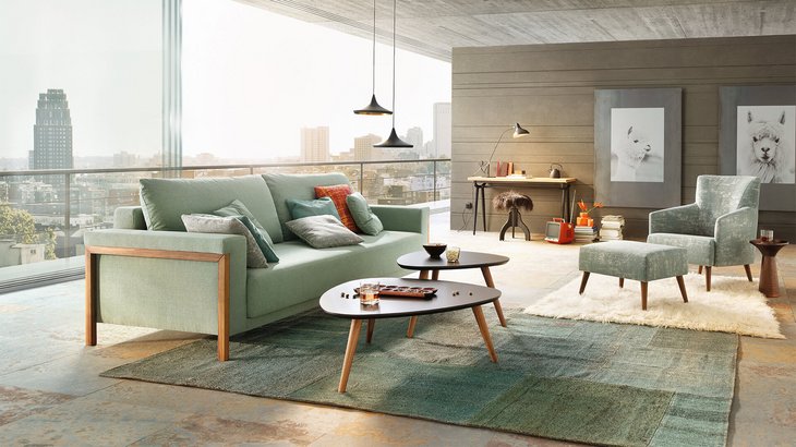 JOKA Time Doppelliege in Mintgrün mit Holzakzenten in geschlossener Sitzposition in einem modernen Loft mit großem Fensterfront-Ausblick.