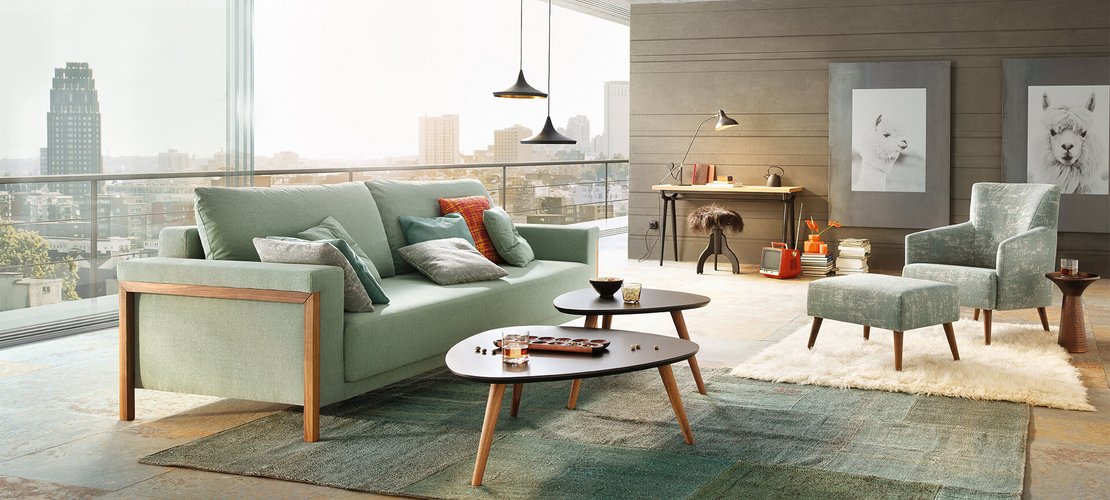 JOKA Time Doppelliege in Mintgrün mit Holzakzenten in geschlossener Sitzposition in einem modernen Loft mit großem Fensterfront-Ausblick.