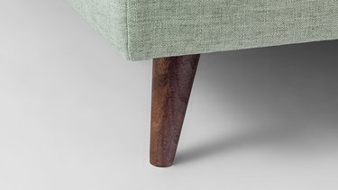 Detailansicht eines schräg angestellten Kegelfusses aus Holz an einer hellgrünen Liege