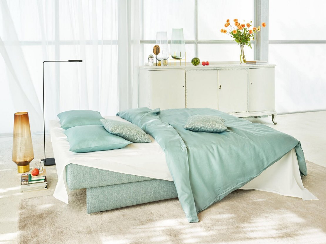 JOKA Perla Doppelliege in Mintgrün, zu einem Bett mit Bettwäsche und Kissen ausgeklappt.