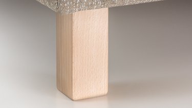 Nahaufnahme eines schmalen, rechteckigen Holzfußes in Quaderform aus hellem Holz.