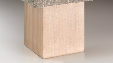 Nahaufnahme eines breiten, quaderförmigen Holzfußes in hellem Naturholz unter der Polsterung.