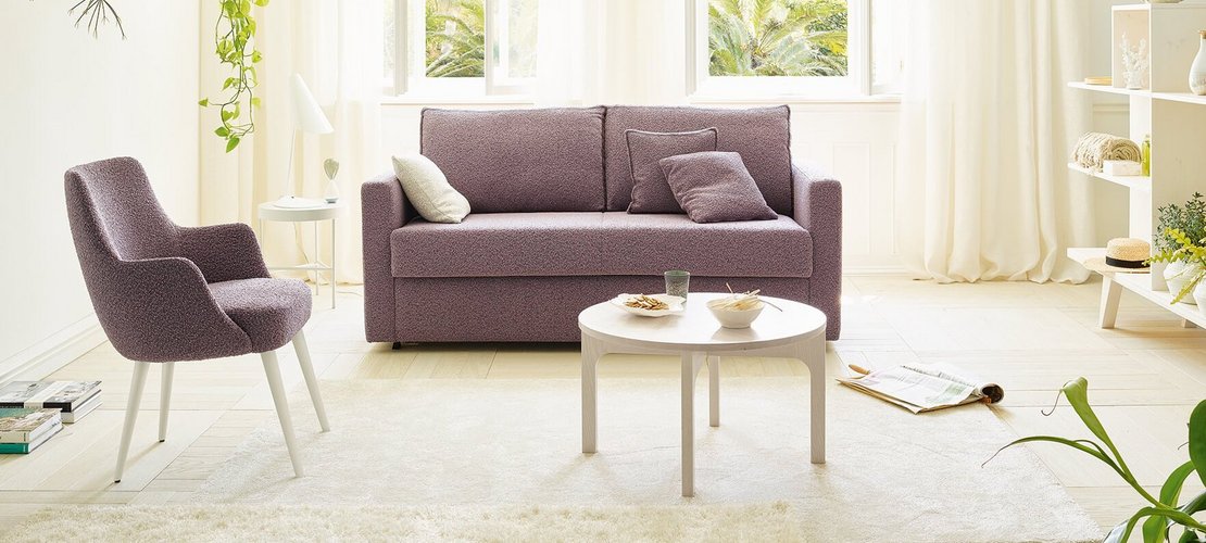 JOKA Onda Doppelliege in Lila in geschlossener Position im hellen Wohnzimmer.