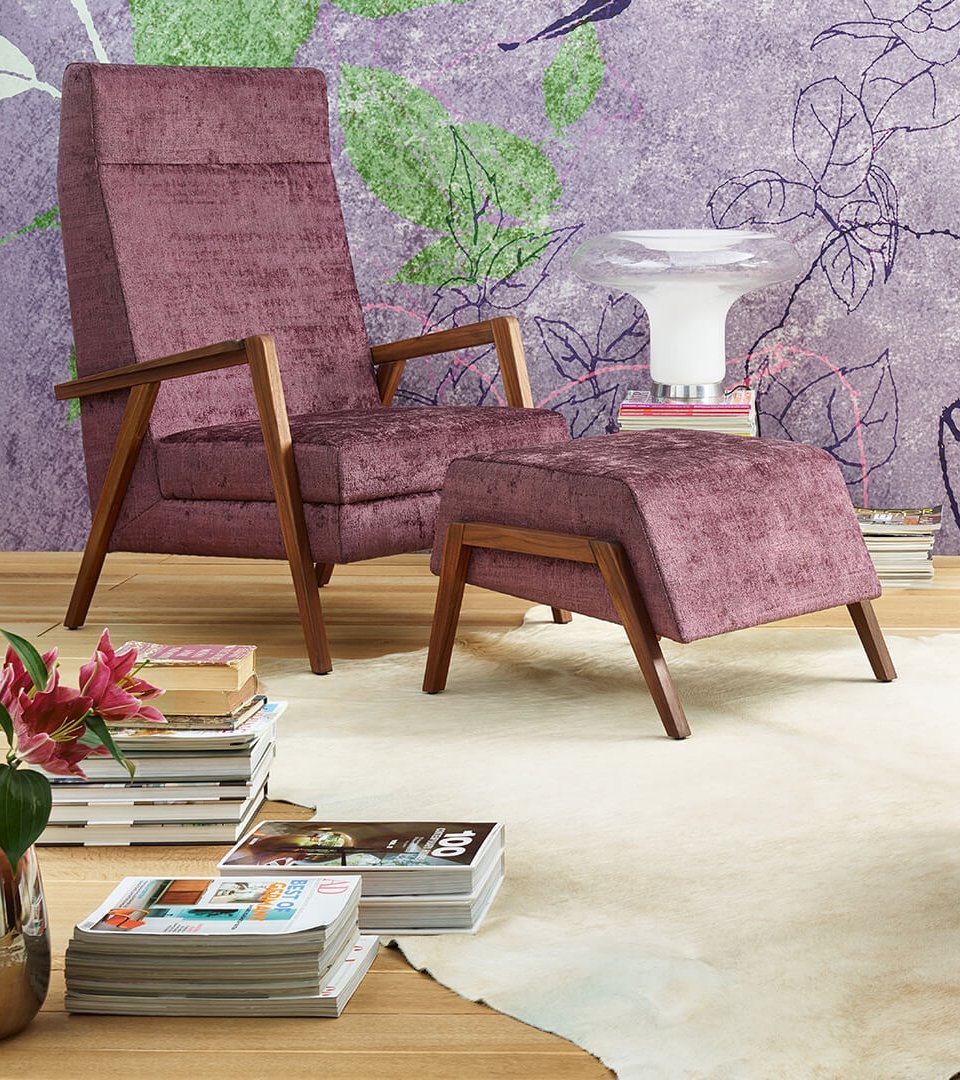 oka Laguna lilafarbener und rosa Fauteuil mit Hocker vor floral gemusterter Tapete