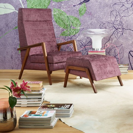 oka Laguna lilafarbener und rosa Fauteuil mit Hocker vor floral gemusterter Tapete
