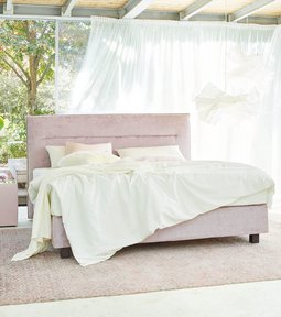 JOKA Capri Boxspringbett in Altrosa in der Totalen im modernen, lichtdurchfluteten Schlafzimmer mit Holzdecke
