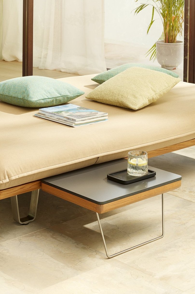 Das Bild zeigt das JOKA Butterfly Sunbed in flacher Position mit einem integrierten kleinen Tisch.