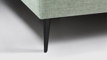 Nahaufnahme eines schlanken, schwarzen Aluminiumfußes an der hellgrün gepolsterten JOKA Toscana Einzelliege