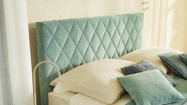 Detailansicht vom gepolsterten JOKA Noblesse Kopfhaupt in Mintgrün mit eleganter Rautensteppung und Kissen
