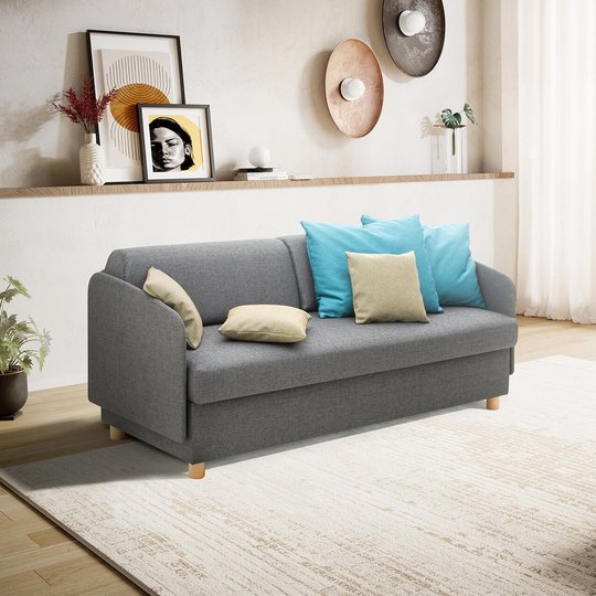 Gesamtansicht des grauen JOKA Pure Allraumbetts mit dreiseitigem Umbau und bunten Rückenkissen im Wohnzimmer